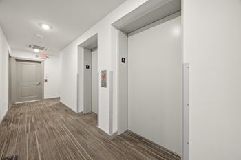 A corridor with white walls and white doors and a wood flooring